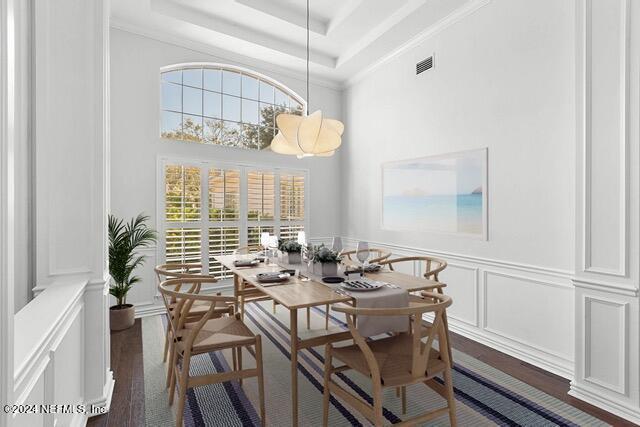 dining room with a tray ceiling, crown molding, and dark wood-type flooring