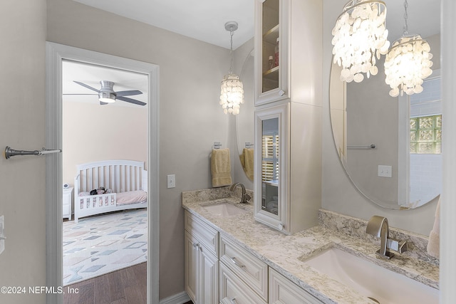 bathroom with ceiling fan with notable chandelier, vanity, and hardwood / wood-style flooring