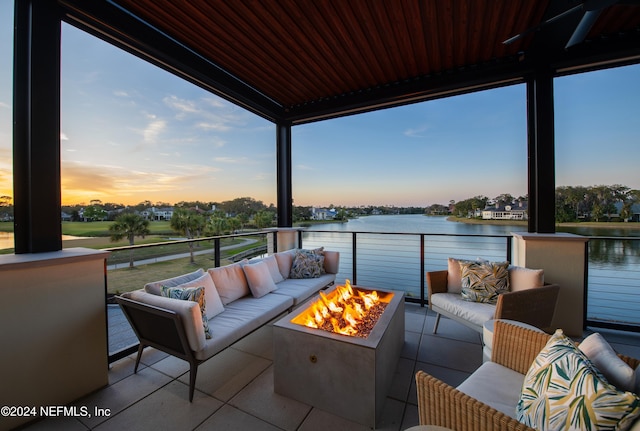 patio terrace at dusk featuring outdoor lounge area, a balcony, and a water view