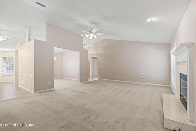 unfurnished living room featuring ceiling fan, light colored carpet, a textured ceiling, and a tiled fireplace