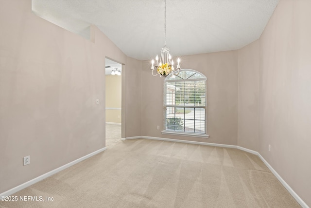 carpeted empty room with lofted ceiling and an inviting chandelier