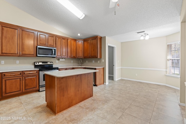 kitchen with sink, vaulted ceiling, a textured ceiling, appliances with stainless steel finishes, and a kitchen island