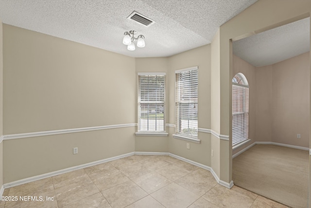 unfurnished room featuring a notable chandelier, light tile patterned floors, and a textured ceiling