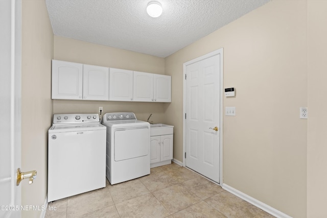 washroom with cabinets, independent washer and dryer, a textured ceiling, and light tile patterned floors