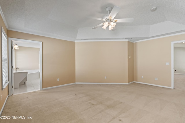 unfurnished bedroom featuring ornamental molding, light colored carpet, a raised ceiling, ceiling fan, and connected bathroom