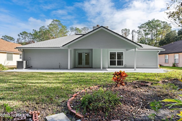 back of property with central air condition unit, french doors, and a lawn