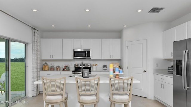 kitchen with white cabinets, stainless steel appliances, a kitchen island with sink, and sink