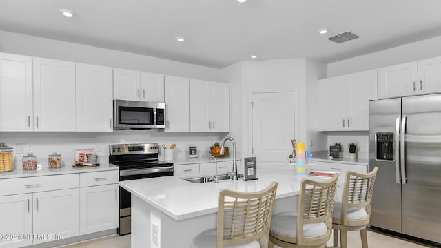 kitchen featuring a kitchen bar, stainless steel appliances, sink, light tile patterned floors, and a center island with sink