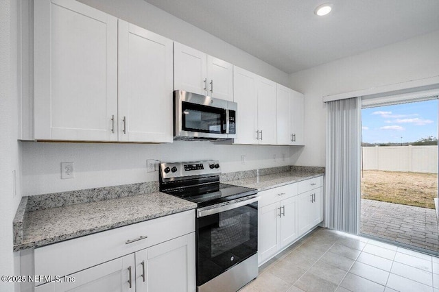 kitchen with light stone counters, light tile patterned floors, stainless steel appliances, and white cabinets