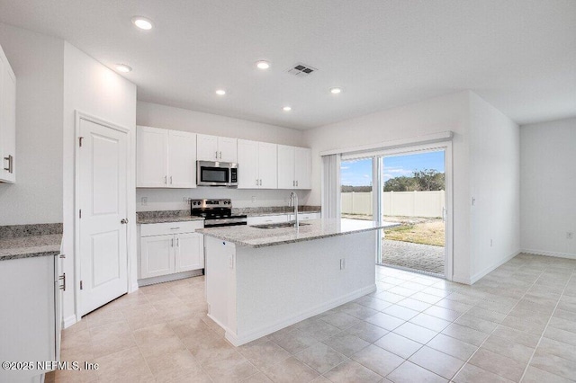 kitchen featuring sink, white cabinets, a kitchen island with sink, light stone counters, and stainless steel appliances