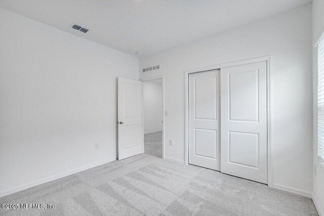 unfurnished bedroom featuring light carpet and a closet