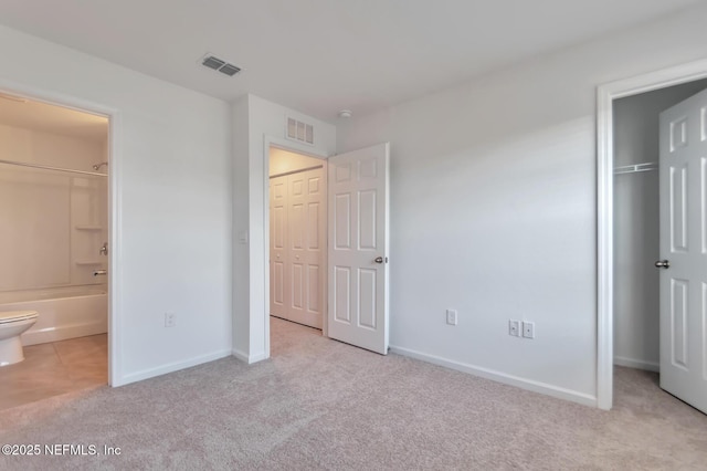 unfurnished bedroom with ensuite bathroom and light carpet