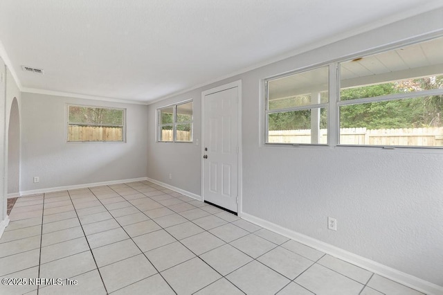 unfurnished room with crown molding, light tile patterned floors, and a healthy amount of sunlight