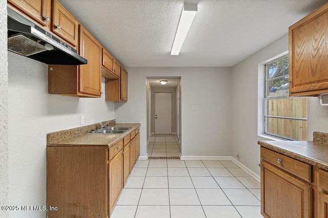 kitchen with sink, light tile patterned flooring, and a textured ceiling