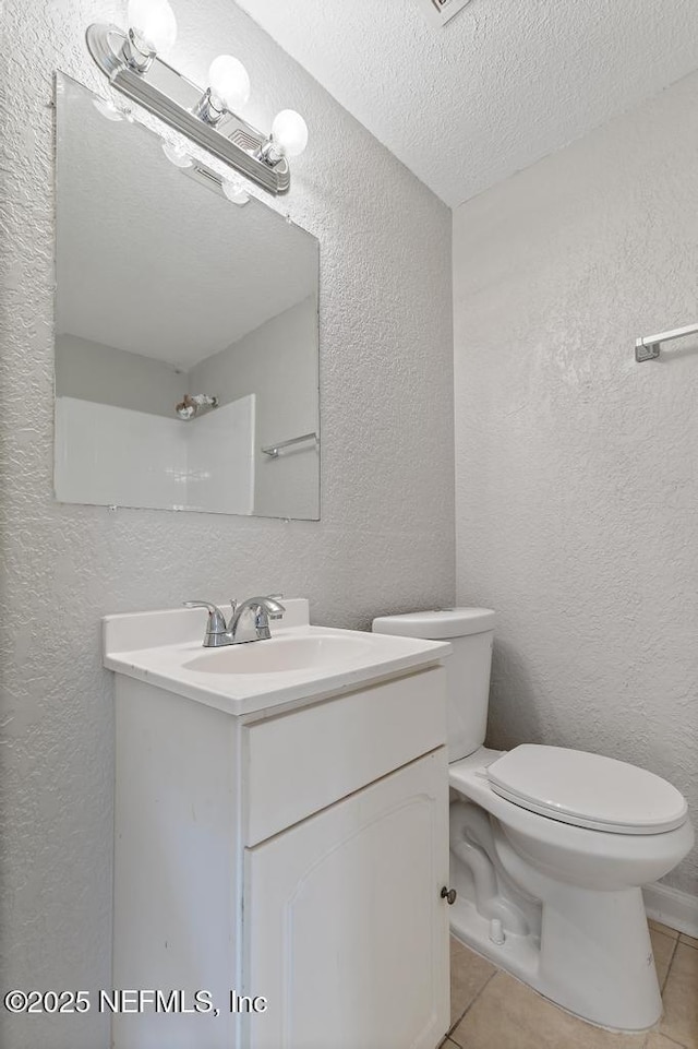 bathroom with tile patterned floors, vanity, a textured ceiling, and toilet