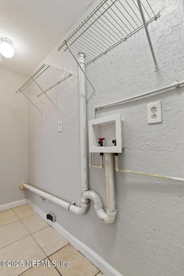 laundry room featuring tile patterned flooring, a textured ceiling, and hookup for a washing machine