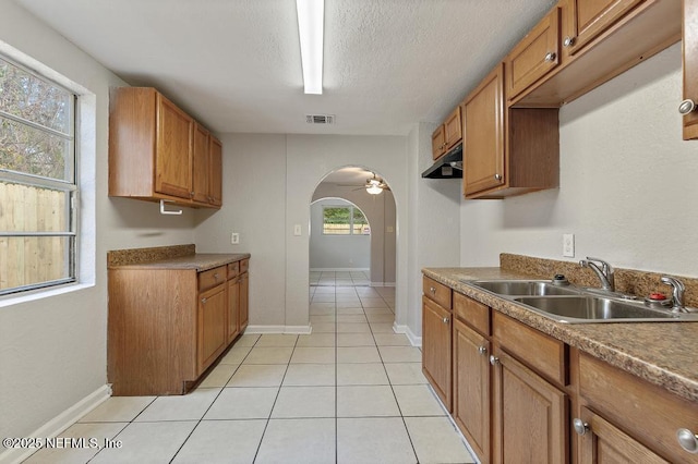 kitchen featuring light tile patterned floors, a textured ceiling, ceiling fan, and sink