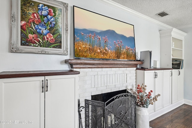 details featuring a fireplace, wood-type flooring, ornamental molding, and a textured ceiling