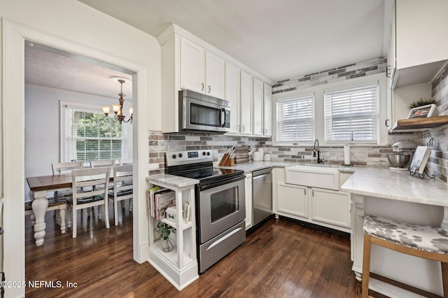 kitchen featuring white cabinets, sink, stainless steel appliances, and an inviting chandelier