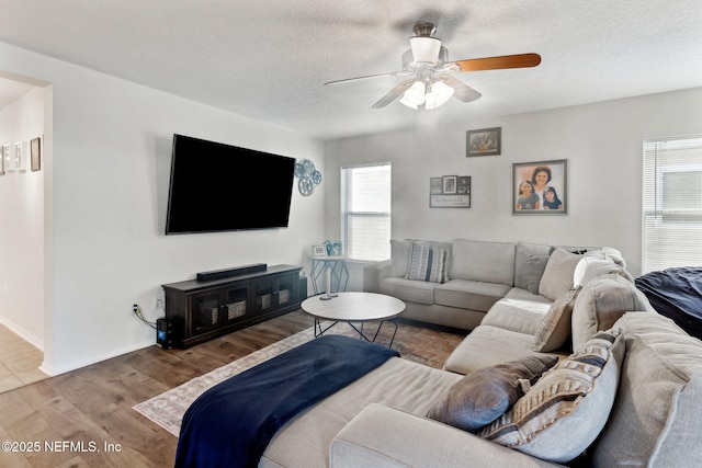 living room featuring wood-type flooring, a textured ceiling, and ceiling fan