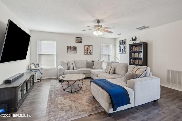 living room featuring ceiling fan, dark hardwood / wood-style flooring, and a textured ceiling