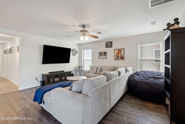 living room with ceiling fan, dark hardwood / wood-style flooring, and a textured ceiling