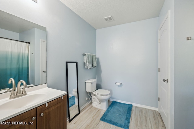 bathroom featuring vanity, toilet, wood-type flooring, and a textured ceiling