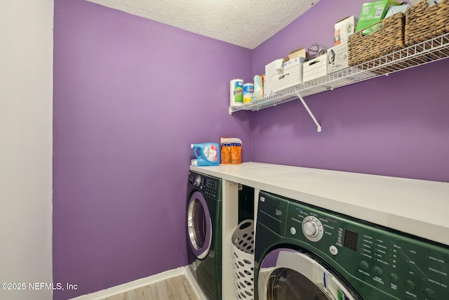 clothes washing area featuring a textured ceiling, light hardwood / wood-style floors, and washing machine and dryer