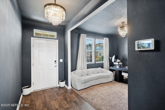 foyer featuring dark wood-type flooring, a textured ceiling, and an inviting chandelier