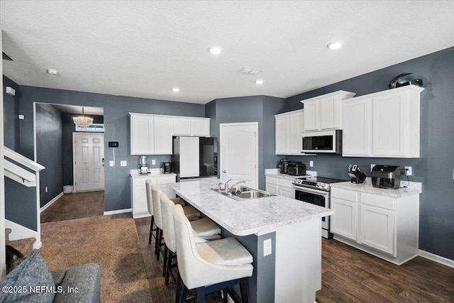 kitchen with white cabinetry, sink, stainless steel range with electric stovetop, fridge, and a center island with sink