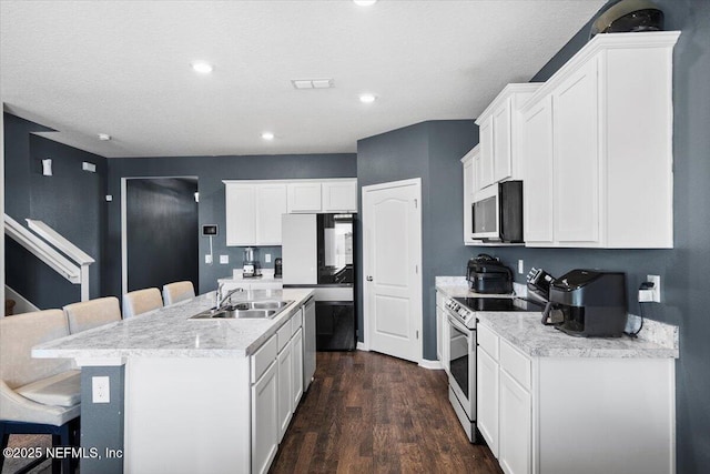 kitchen with sink, dark wood-type flooring, white electric stove, a kitchen island with sink, and a breakfast bar