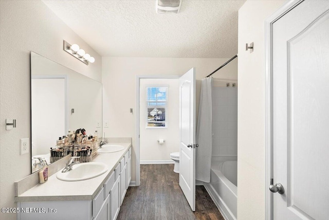 full bathroom with vanity, a textured ceiling, wood-type flooring, shower / bathtub combination with curtain, and toilet