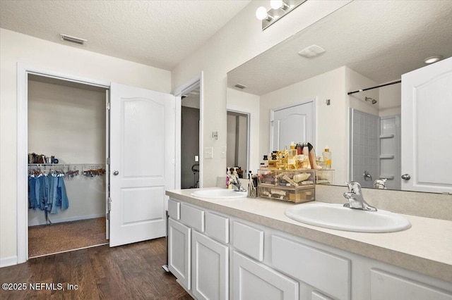 bathroom with vanity, wood-type flooring, a textured ceiling, and walk in shower