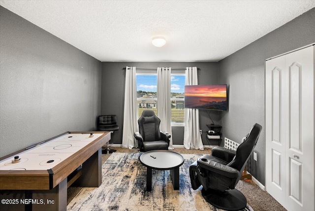 game room featuring light colored carpet and a textured ceiling