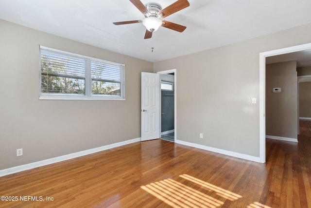 unfurnished bedroom with a walk in closet, ceiling fan, and dark hardwood / wood-style flooring