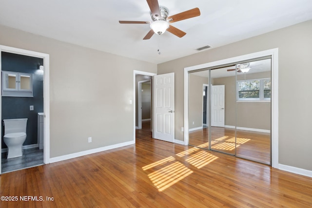 unfurnished bedroom with hardwood / wood-style floors, ensuite bath, a closet, and ceiling fan