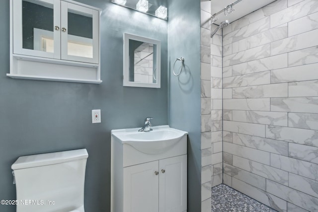 bathroom with vanity, toilet, and a tile shower