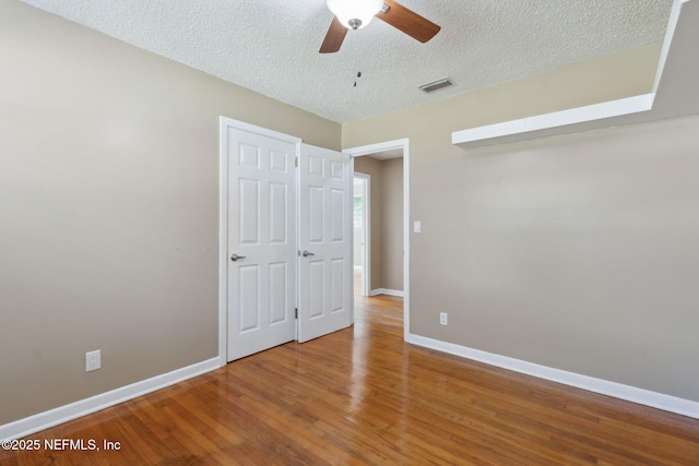 unfurnished bedroom with ceiling fan, wood-type flooring, and a textured ceiling