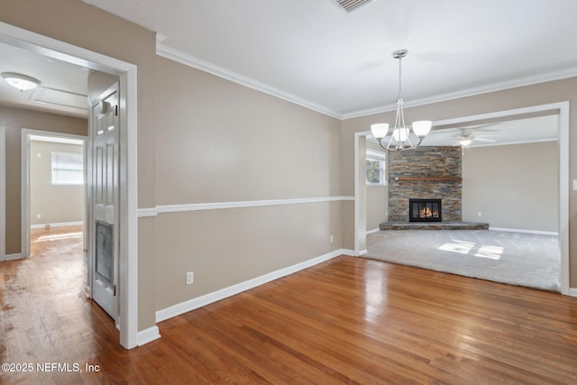 unfurnished living room with a fireplace, wood-type flooring, ceiling fan with notable chandelier, and ornamental molding