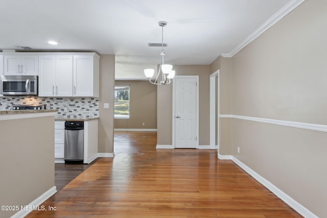 kitchen with an inviting chandelier, pendant lighting, decorative backsplash, white cabinets, and hardwood / wood-style flooring