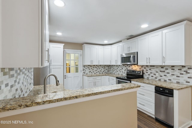 kitchen featuring backsplash, white cabinetry, light stone counters, kitchen peninsula, and stainless steel appliances