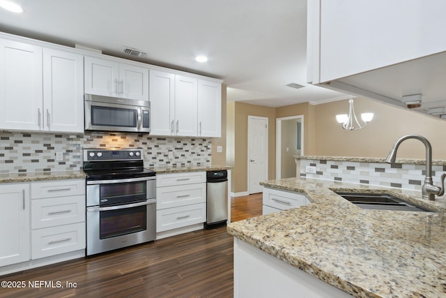 kitchen featuring sink, stainless steel appliances, pendant lighting, decorative backsplash, and white cabinets