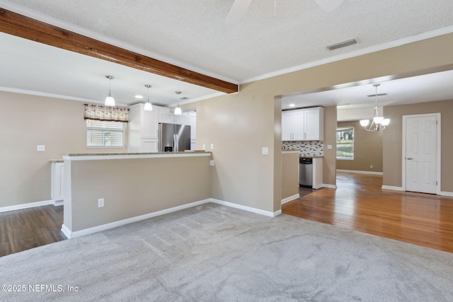 unfurnished living room featuring beamed ceiling, light colored carpet, a textured ceiling, ceiling fan with notable chandelier, and ornamental molding