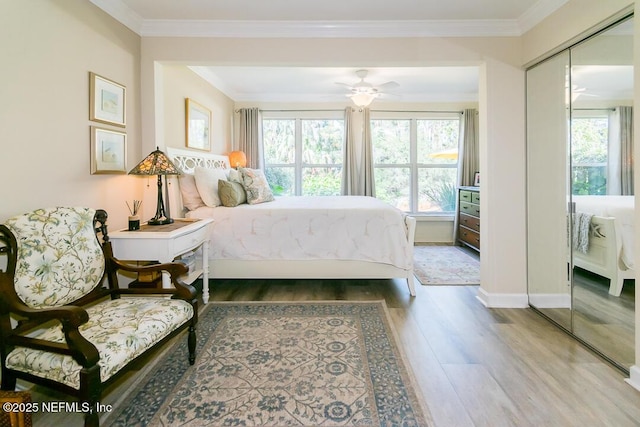 bedroom featuring hardwood / wood-style flooring, ceiling fan, crown molding, and a closet