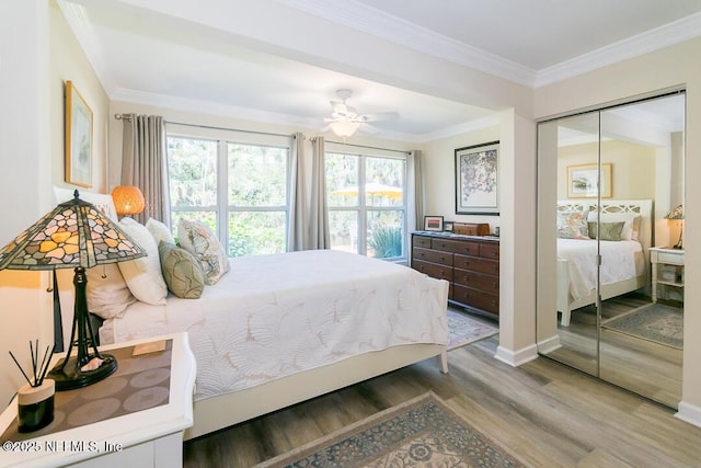 bedroom featuring wood-type flooring, a closet, ceiling fan, and ornamental molding