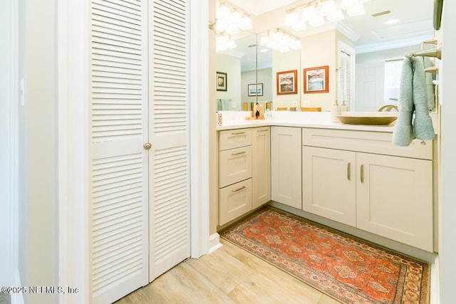 bathroom featuring a chandelier, vanity, hardwood / wood-style flooring, and ornamental molding