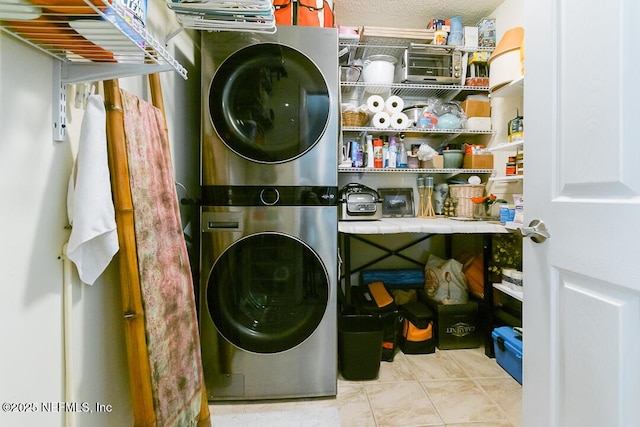 clothes washing area with light tile patterned floors, a textured ceiling, and stacked washer and clothes dryer