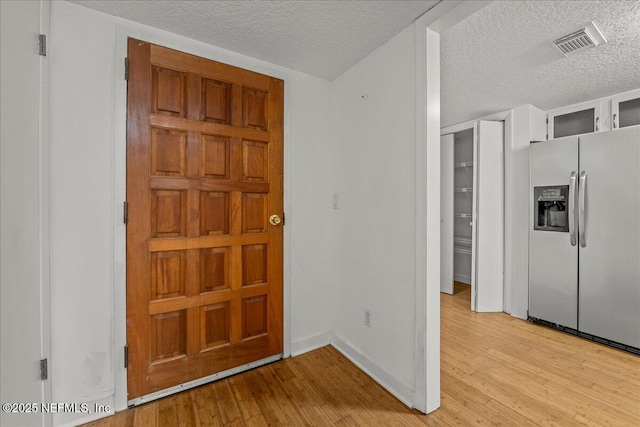 foyer entrance with a textured ceiling and light wood-type flooring