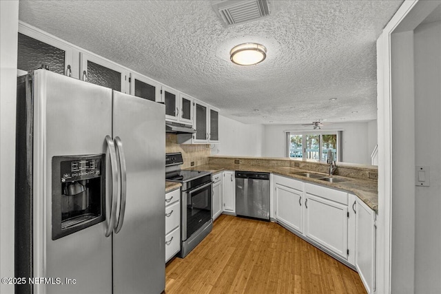 kitchen featuring white cabinetry, sink, light hardwood / wood-style floors, decorative backsplash, and appliances with stainless steel finishes