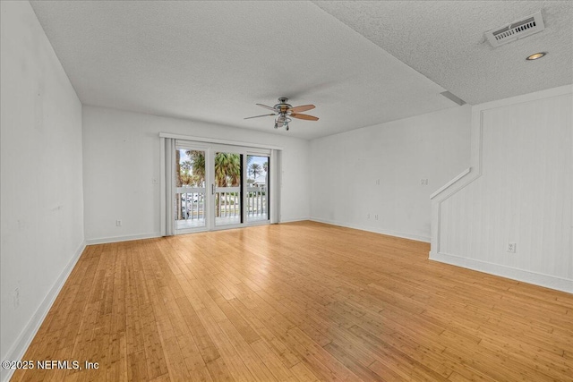 empty room featuring a textured ceiling, light hardwood / wood-style floors, and ceiling fan